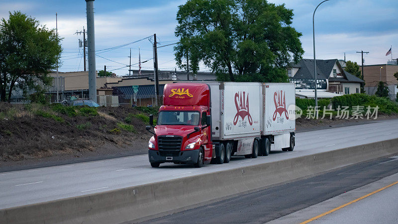 Saia LTL货运半卡车，带双拖车，沿着90号州际公路行驶，穿过市区。